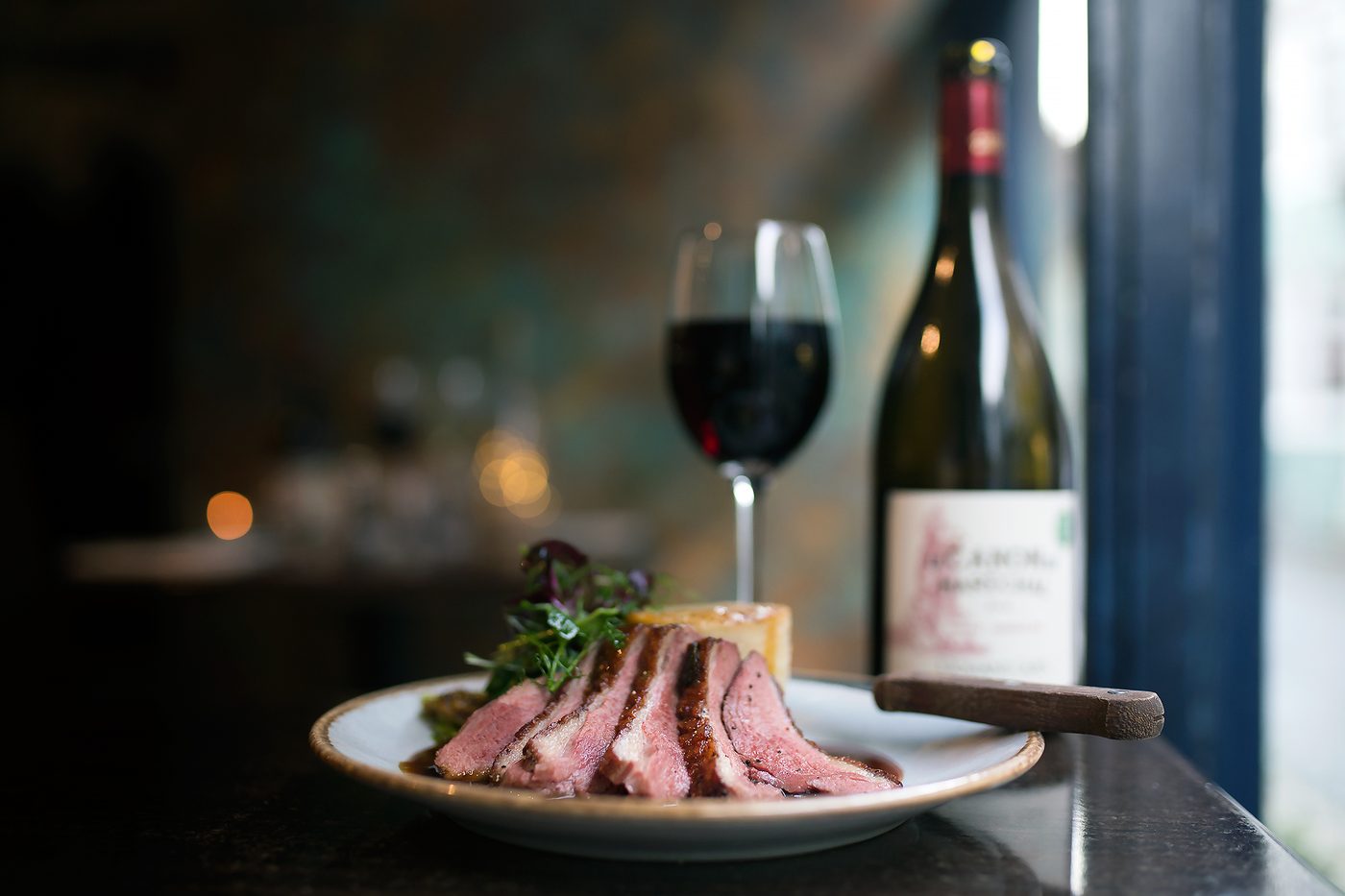 Sliced duck breast with a glass of red wine