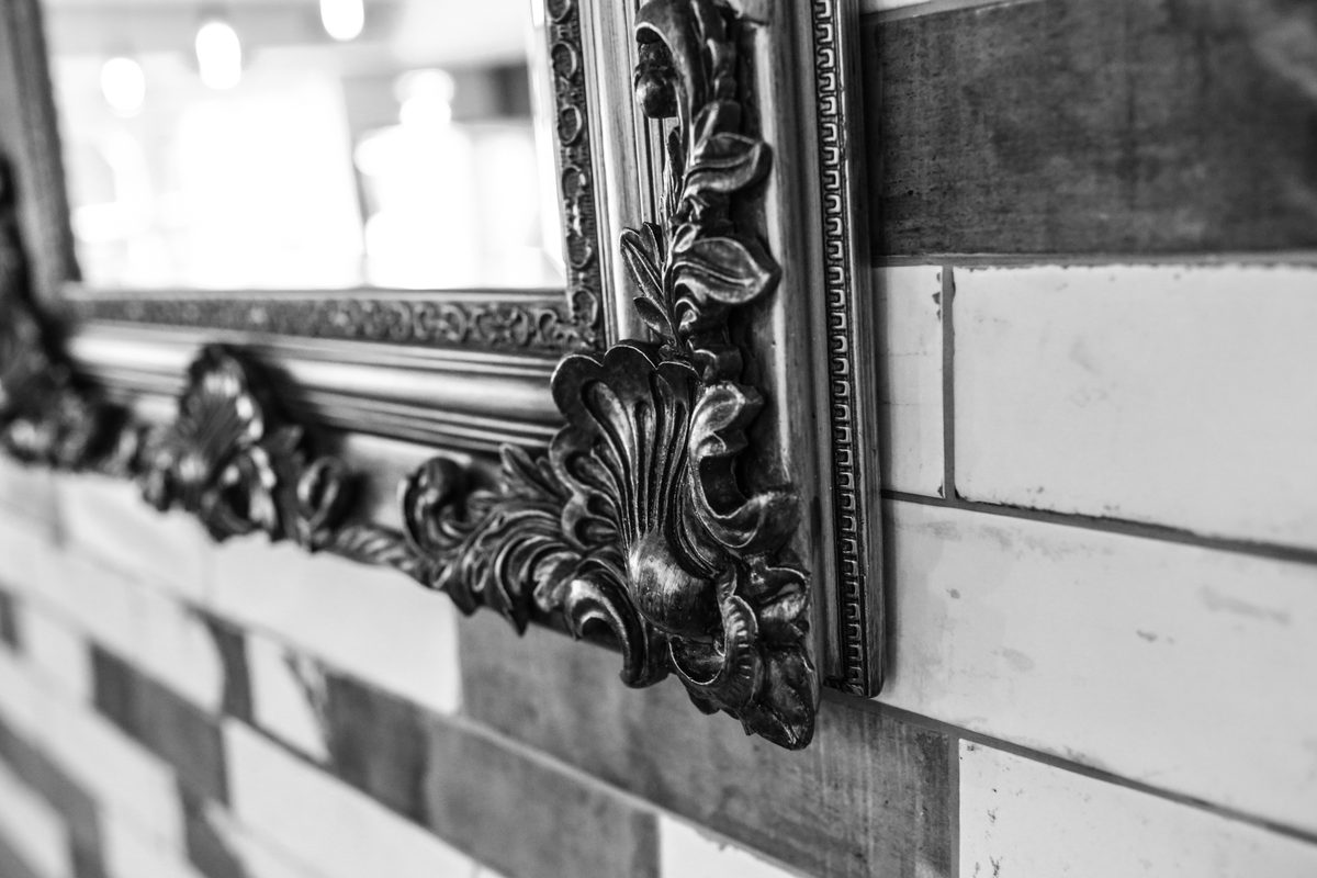 An ornate gilt mirror on the white-painted brick of the dining room