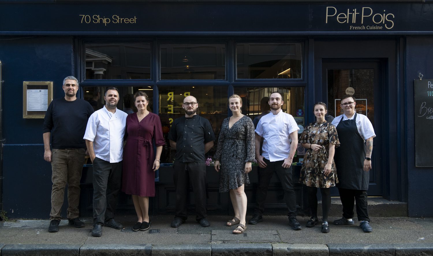 The Petit Pois team lined up beneath the gold lettering of the fascia